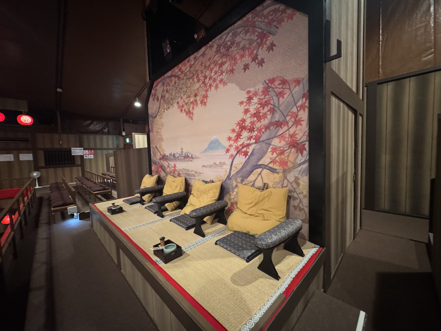 平成中村座のお大尽席の座席。紅葉と富士山の描かれた背景に金屏風風の座布団と肘掛け、お茶道具が並ぶ